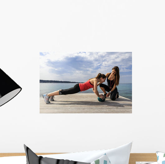 Young woman doing push-ups on a medicine ball with a coach Wall Decal