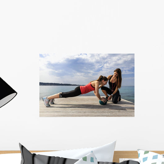 Young woman doing push-ups on a medicine ball with a coach Wall Decal