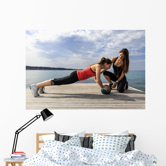 Young woman doing push-ups on a medicine ball with a coach Wall Decal