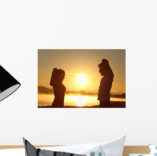 Silhouette of a fitness couple stretching at sunrise Wall Decal