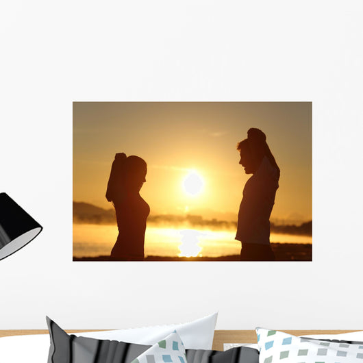 Silhouette of a fitness couple stretching at sunrise Wall Decal