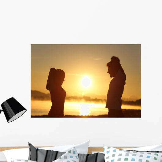 Silhouette of a fitness couple stretching at sunrise Wall Decal