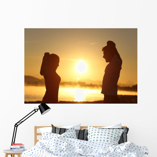 Silhouette of a fitness couple stretching at sunrise Wall Decal