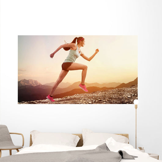 Junge joggerin läuft auf berg Wall Mural