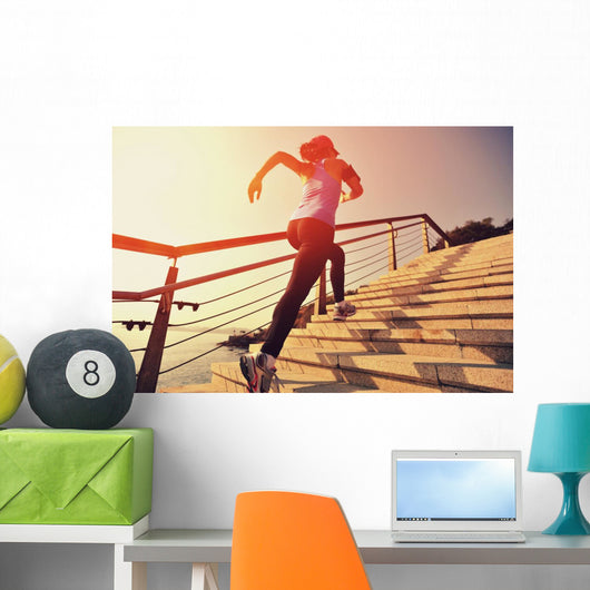 young fitness woman running on seaside stone stairs Wall Mural
