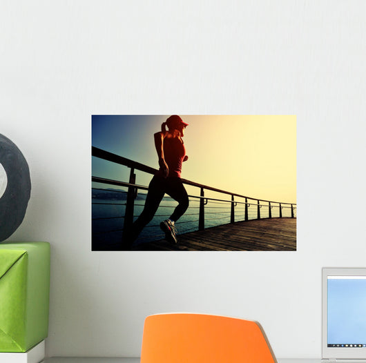 young fitness woman running on sunrise seaside boardwalk Wall Mural