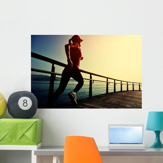 young fitness woman running on sunrise seaside boardwalk Wall Mural