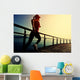 young fitness woman running on sunrise seaside boardwalk Wall Mural