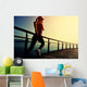 young fitness woman running on sunrise seaside boardwalk Wall Mural