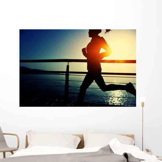 young fitness woman running on sunrise seaside boardwalk Wall Mural