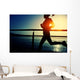 young fitness woman running on sunrise seaside boardwalk Wall Mural