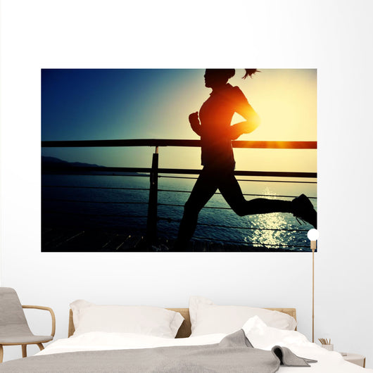 young fitness woman running on sunrise seaside boardwalk Wall Mural