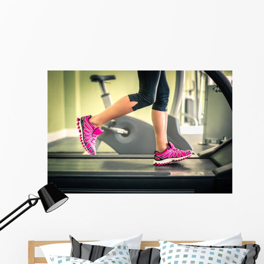 Fitness girl running on treadmill. With muscular legs in gym. Wall Mural