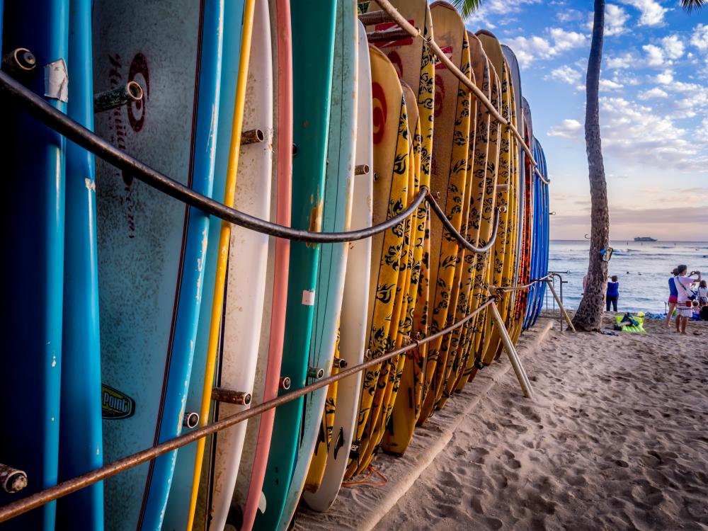 Colorful Surfboards Stacked Up On Waikiki Beach At Sunset. Wall