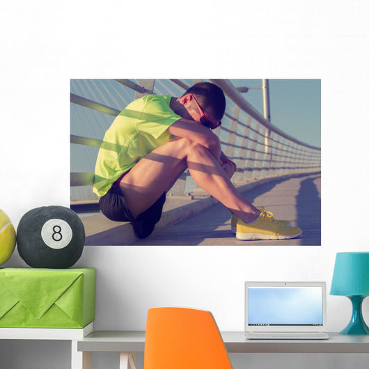 Tired/injured jogger on a big bridge. Wall Mural
