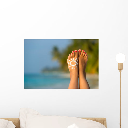 Woman foot with sun-shaped sun cream in the tropical beach Wall Mural