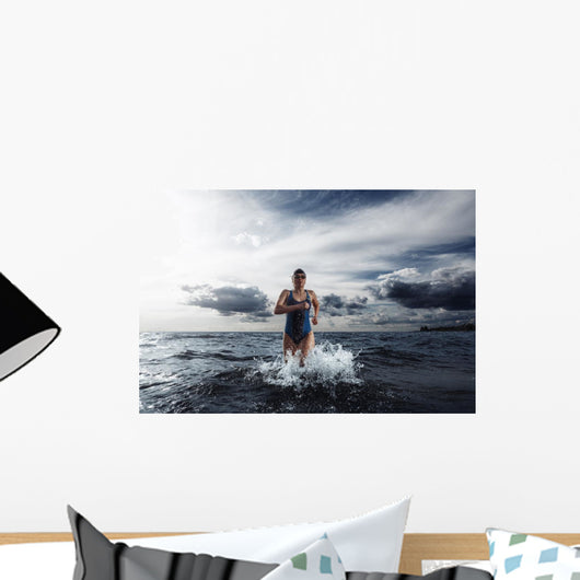 Young woman athlete running out of water Wall Mural