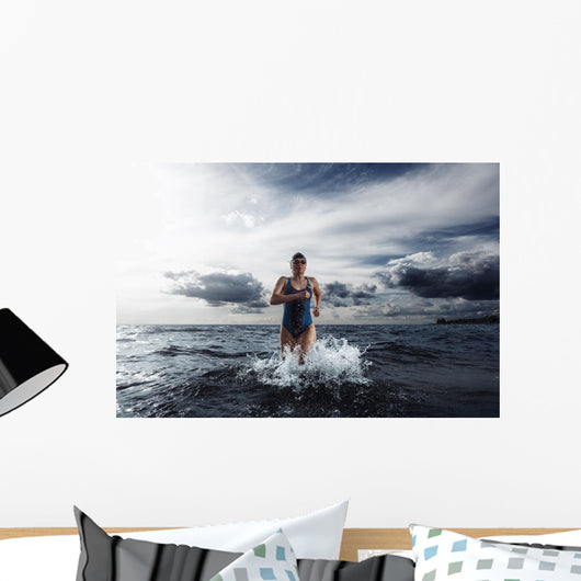 Young woman athlete running out of water Wall Mural