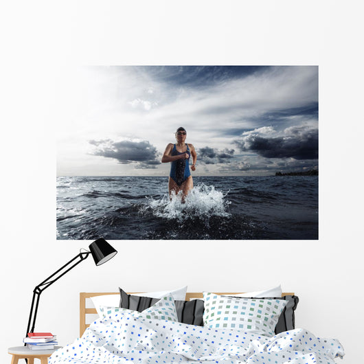 Young woman athlete running out of water Wall Mural