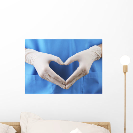 Doctor showing shape of heart by his hands in sterile gloves, Wall Mural