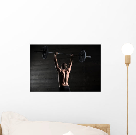 Portrait of a handsome athlete from behind. Athlete raises the b Wall Mural
