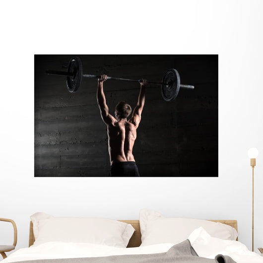 Portrait of a handsome athlete from behind. Athlete raises the b Wall Mural