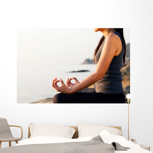The woman meditating in a yoga pose on the tropical beach. Wall Mural