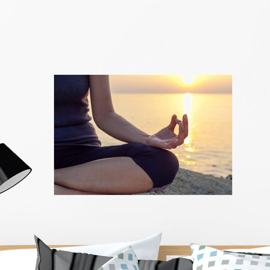The woman meditating in a yoga pose on the tropical beach. Wall Mural