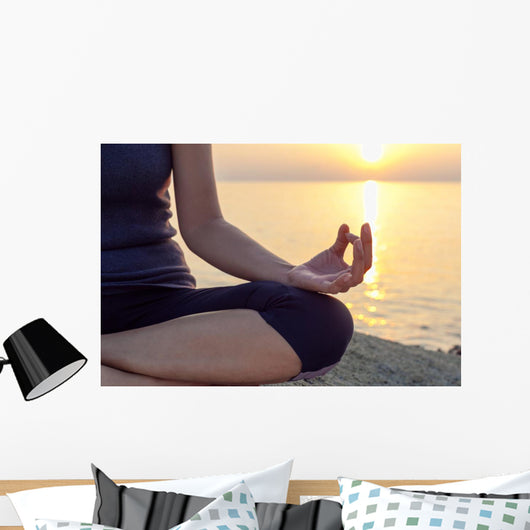 The woman meditating in a yoga pose on the tropical beach. Wall Mural