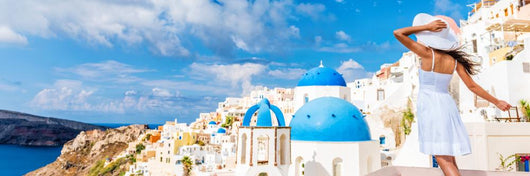 Europe tourist travel woman panorama banner from Oia, Santorini, Greece. Happy young woman looking at famous blue dome church landmark destination. Beautiful girl visiting the Greek islands. Wall Mural