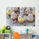 Purple and yellow cupcakes with sugared edible flowers on vintage cake stand Wall Mural