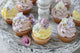 Purple and yellow cupcakes with sugared edible flowers on vintage cake stand Wall Mural