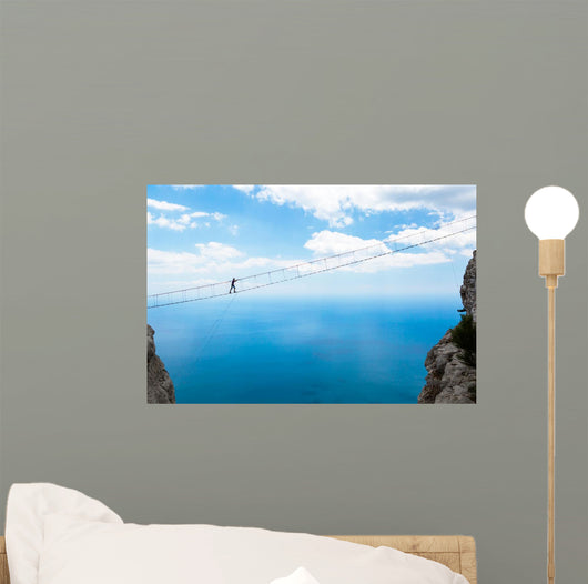 Man climbing on the suspension bridge. Wall Mural