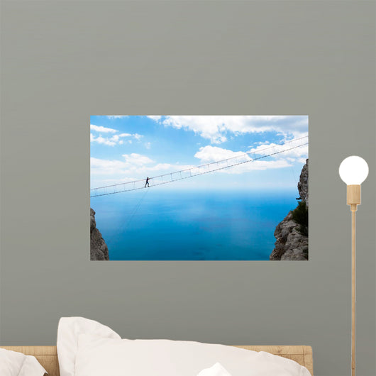 Man climbing on the suspension bridge. Wall Mural