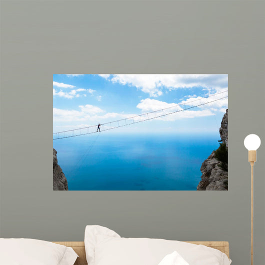 Man climbing on the suspension bridge. Wall Mural