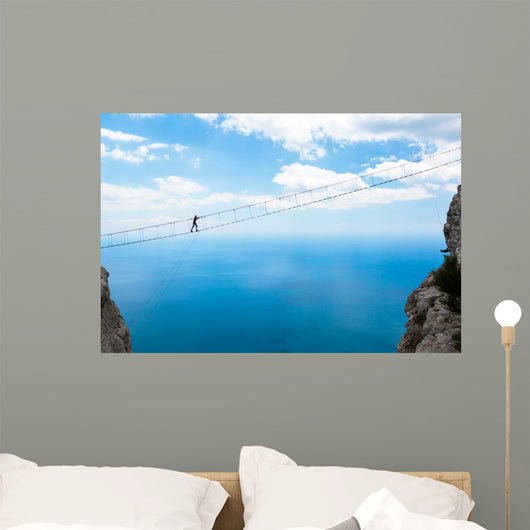 Man climbing on the suspension bridge. Wall Mural