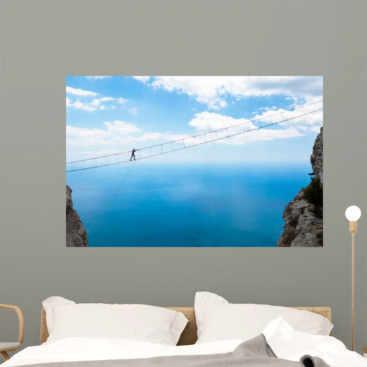 Man climbing on the suspension bridge. Wall Mural