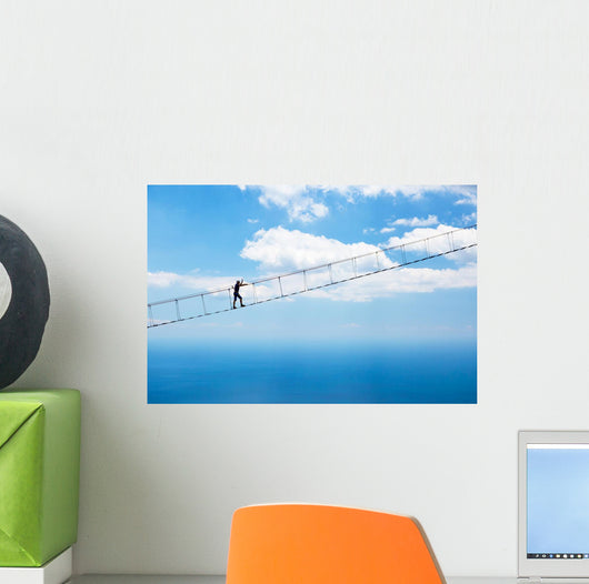 Man climbing on the suspension bridge. Wall Mural