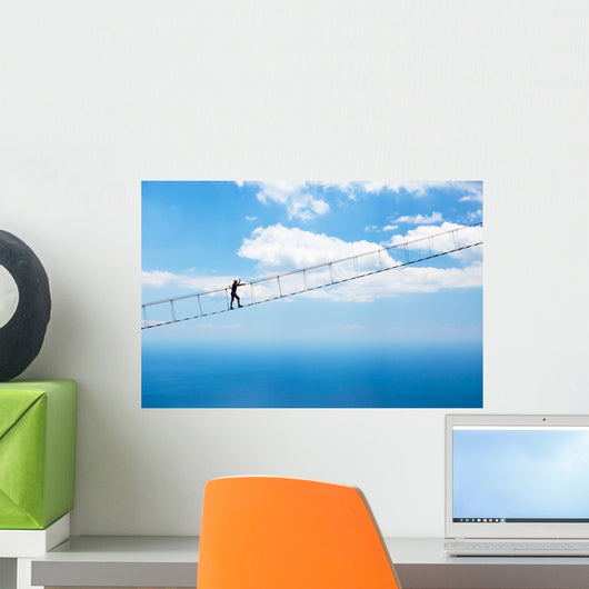 Man climbing on the suspension bridge. Wall Mural