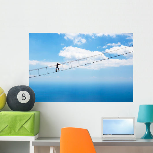 Man climbing on the suspension bridge. Wall Mural