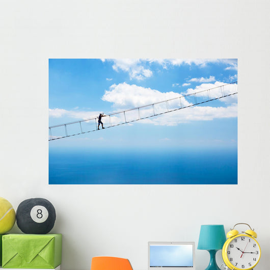 Man climbing on the suspension bridge. Wall Mural