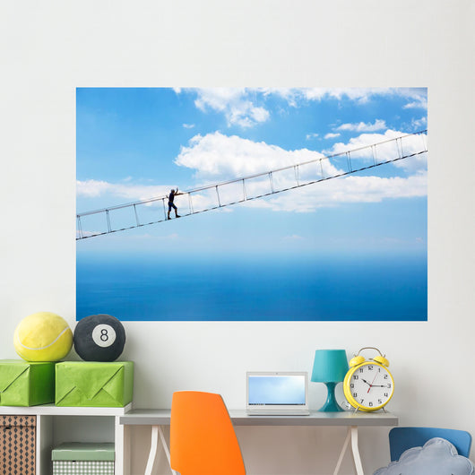 Man climbing on the suspension bridge. Wall Mural