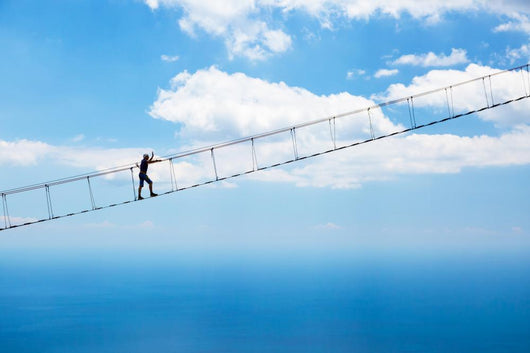 Man climbing on the suspension bridge. Wall Mural