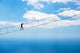 Man climbing on the suspension bridge. Wall Mural