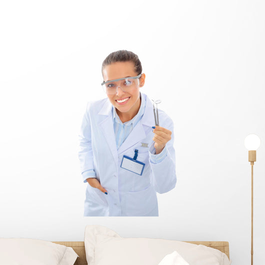 A young dentist with a tool on a white background Wall Decal
