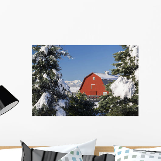 Snow covered red barn, evergreens, mountains Wall Mural