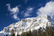 Snow covered mountain peak, blue sky, clouds Wall Mural