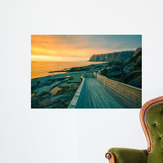 Senja island at orange sunset. Wooden pathway on the rocky beach Wall Mural