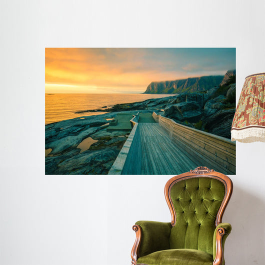 Senja island at orange sunset. Wooden pathway on the rocky beach Wall Mural