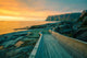 Senja island at orange sunset. Wooden pathway on the rocky beach Wall Mural